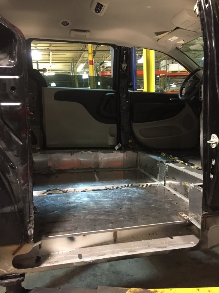 Technicians weld new floor into Dodge Caravan.