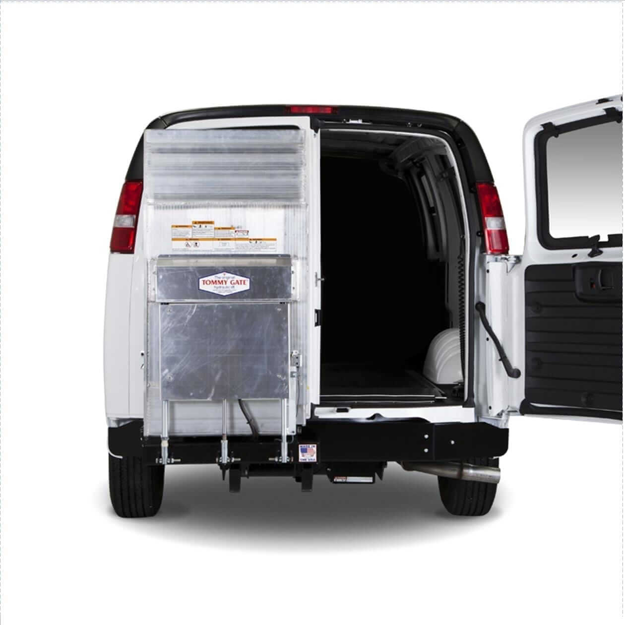 TG-Cant_GM_UP_Main The rear view of a white van with open doors, revealing a cargo space fitted with a lift gate and shelves.
