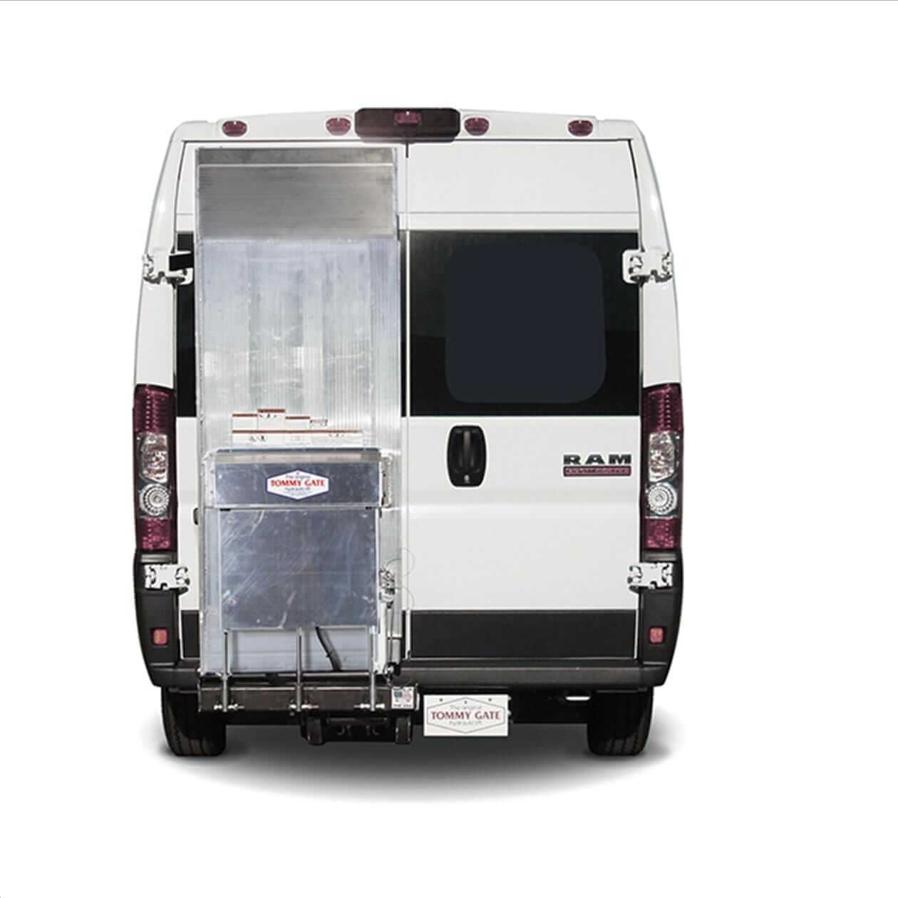 TG-Cant_PM_Up Rear view of a white van with one door open, revealing a metal Tommy Gate lift.