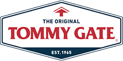 tommygate-logo Logo of Tommy Gate, featuring a white shield with red and blue text, established in 1965.