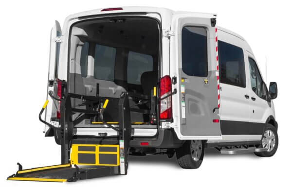 White Ford Paratransit van with rear doors open, showcasing a deployed wheelchair lift.