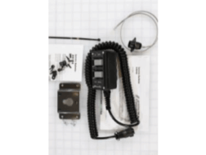 A coiled cable with connector, metal mounting bracket, screws, zip tie, and instruction sheets laid out on a grid-patterned surface.