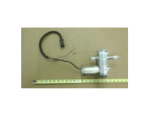 A small mechanical device with attached wires and connector is placed next to a measuring tape on a plain surface.