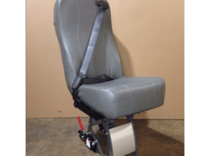 A single gray vehicle seat with an attached seatbelt and metal base is positioned on a concrete floor against a plain brown background.
