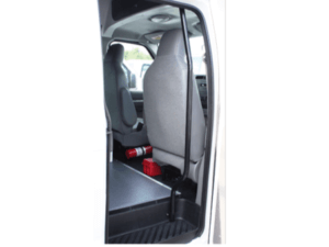Open vehicle door showing the interior with two gray seats, a fire extinguisher, and a red first aid kit on the floor behind the front seats.