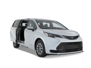 A white Toyota Sienna Hybrid minivan with its rear passenger sliding door open, viewed from the front left side, against a plain white background.