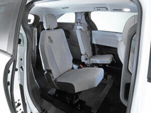 Interior view of a Toyota Sienna Hybrid showing two rows of individual gray fabric seats with ample legroom, a modern, minimalist design, and convenient rear-entry access.