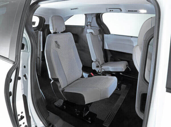 Interior view of a Toyota Sienna Hybrid showing two rows of individual gray fabric seats with ample legroom, a modern, minimalist design, and convenient rear-entry access.