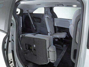 The image shows the interior of a Toyota Sienna Hybrid with the second-row seat folded forward, revealing rear-entry access to the third-row seating area.