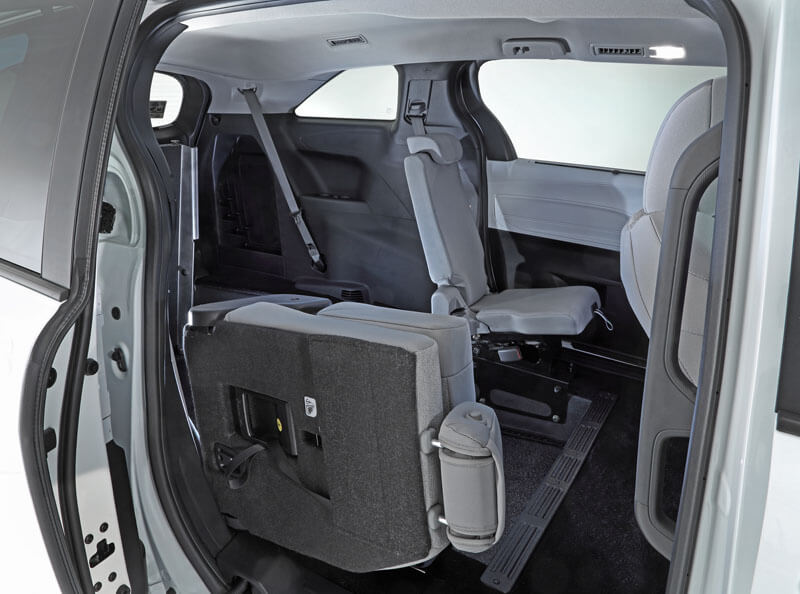 The image shows the interior of a Toyota Sienna Hybrid with the second-row seat folded forward, revealing rear-entry access to the third-row seating area. The image shows the interior of a Toyota Sienna Hybrid with the second-row seat folded forward, revealing rear-entry access to the third-row seating area.