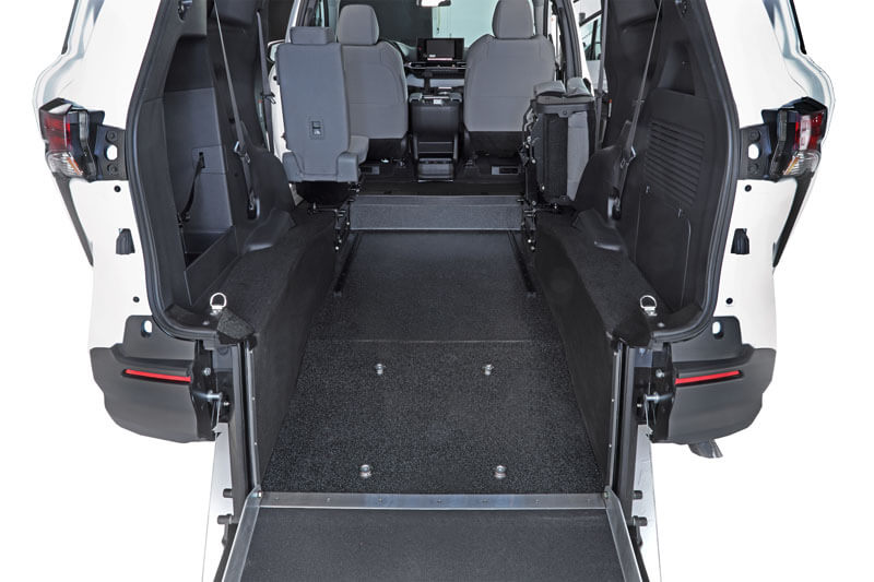 Rear-Entry view of a Toyota Sienna Hybrid wheelchair-accessible van, featuring a lowered floor and ramp, two front seats, and an open space for wheelchair placement. Rear-Entry view of a Toyota Sienna Hybrid wheelchair-accessible van, featuring a lowered floor and ramp, two front seats, and an open space for wheelchair placement.