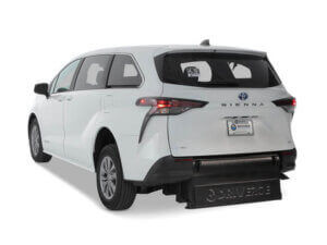 A white Toyota Sienna Hybrid minivan with a rear-entry wheelchair ramp extended from the back, shown on a plain white background.
