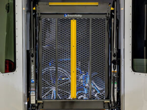 A rear view of a van with open doors, showing a BraunAbility wheelchair lift in the lowered position, ready for use.